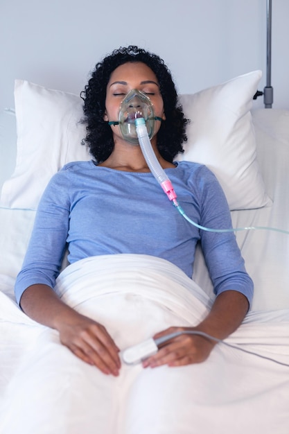 Paciente afro-americana dormindo na cama do hospital com ventilador de oxigênio