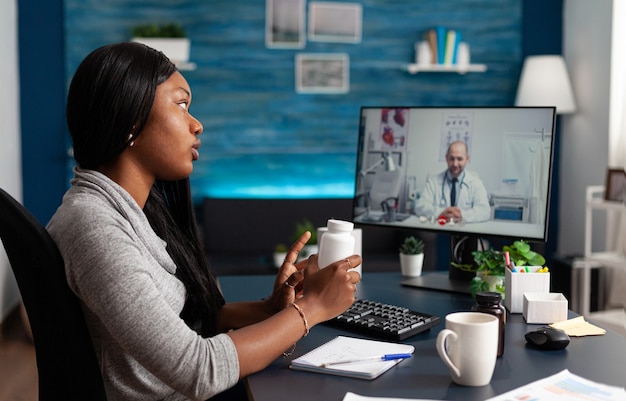 Paciente afro-americano com consulta médica para discutir tratamento de saúde de pílulas com médico.