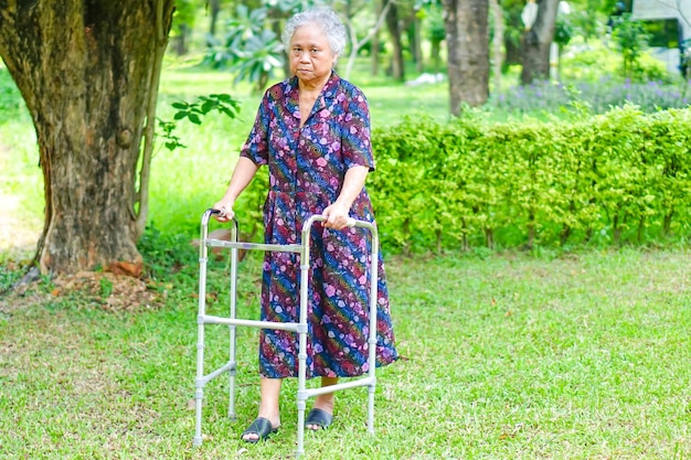 Paciente anciana asiática camina con andador en el parque concepto médico fuerte y saludable