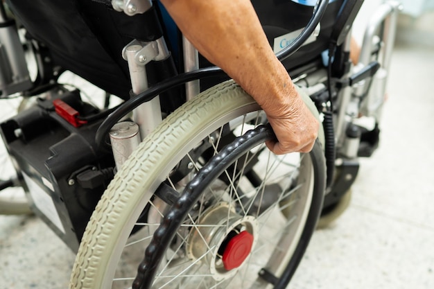 Paciente anciana asiática en silla de ruedas eléctrica con control remoto en el hospital concepto médico fuerte y saludable