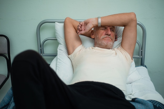 Paciente anciano descansando en la cama en el hospital.