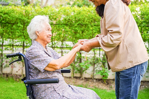 Paciente asiática con discapacidad anciana sentada en silla de ruedas en el concepto médico del parque