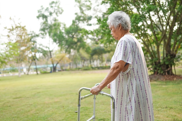 Paciente asiático mulher idosa sênior ou idosa andar com walker no parque: conceito médico forte saudável