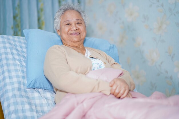 Paciente asiático senior mujer sentada en la cama en el hospital