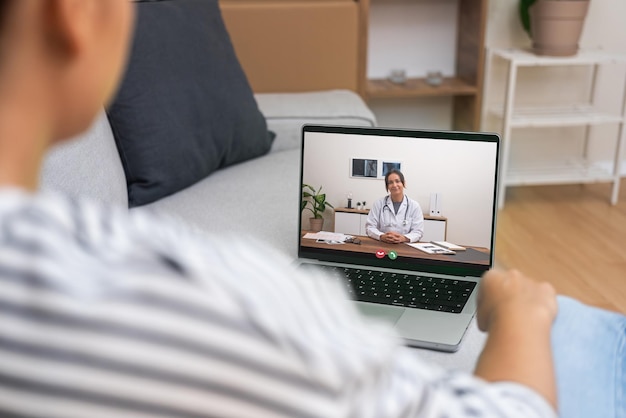 Paciente en casa en un entorno relajado interactuando con un médico en una computadora portátil que representa la conveniencia