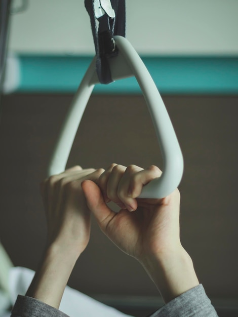 Paciente caucasiano segura com as duas mãos em um arco terapêutico triangular com uma pinça