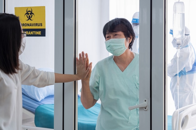 Paciente com infecção por coronavírus na sala de quarentena de pressão negativa com sinal de alerta de quarentena no hospital se sente feliz e alegre com o membro da família.