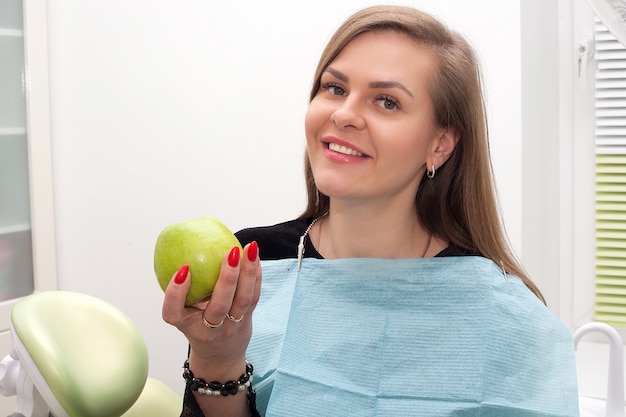 Paciente en el consultorio dental con una manzana verde en sus manos