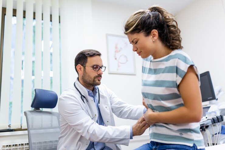 Paciente contando ao médico sobre sua dor e problemas de saúde durante a visita ao hospital Mulher jovem queixando-se de dor nas costas ou nos rins enquanto estava sentada na cama de exame no consultório do médico