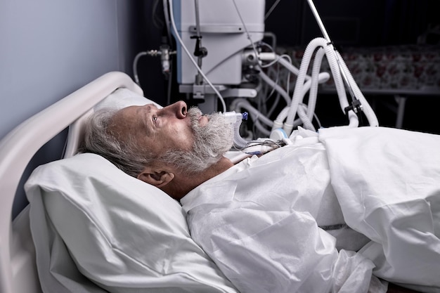 Paciente con Covid-19 con tubo endotraqueal en la boca acostado en un sillón médico, cama