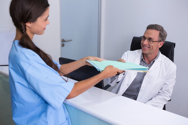 Foto paciente dando arquivos ao dentista