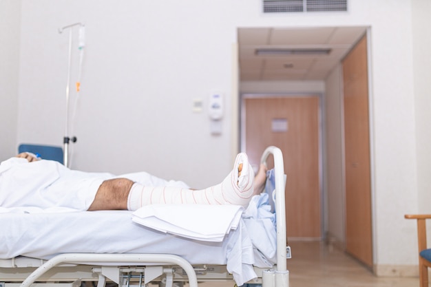 Foto paciente deitado na cama de hospital com a perna quebrada. hospitalização e conceito de assistência médica.