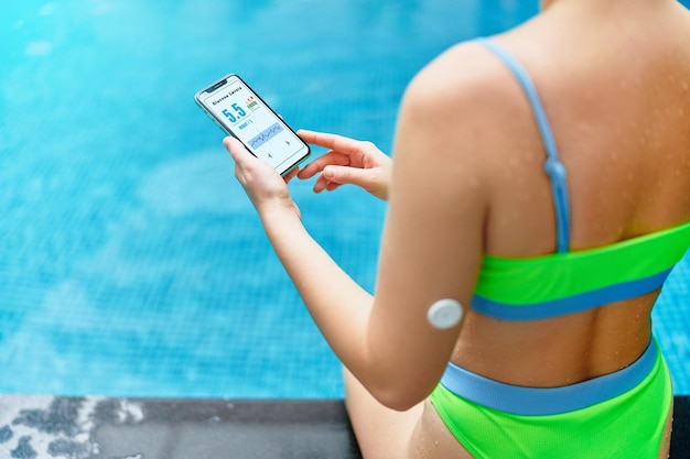 Paciente diabético de aptidão atlética ativa monitorando o nível de glicose com sensor remoto durante o treinamento na piscina tecnologia médica inteligente no tratamento do diabetes espaço para texto