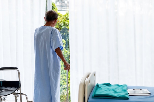 Foto paciente do homem sênior com a bengala no quarto de hospital.