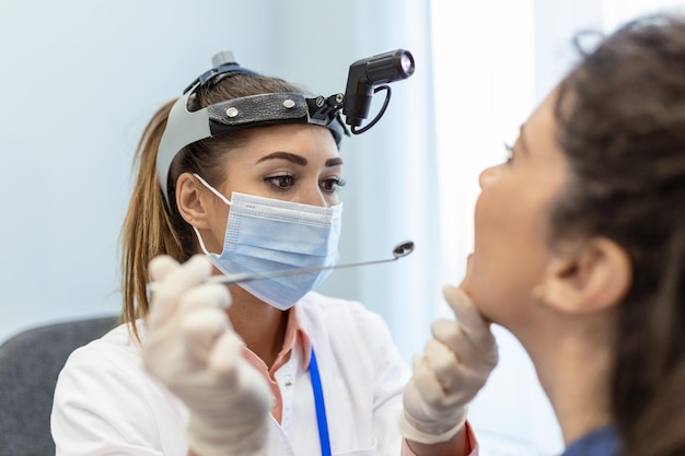 Paciente do sexo feminino abrindo a boca para o médico olhar em sua garganta Médica examinando dor de garganta do paciente na clínica Otorrinolaringologista examina dor de garganta do paciente