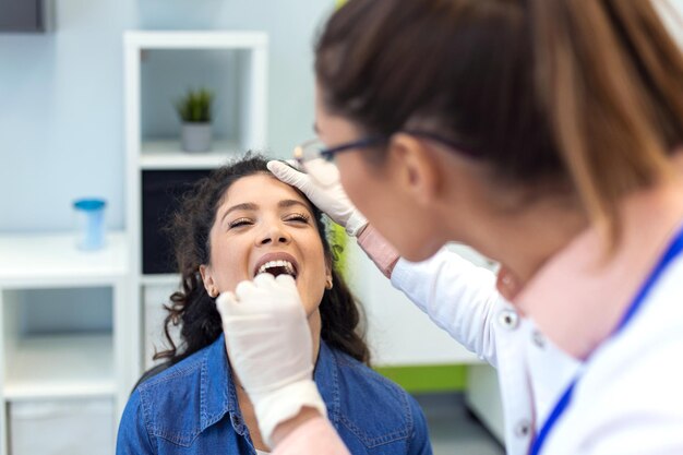 Paciente do sexo feminino abrindo a boca para o médico olhar em sua garganta Médica examinando dor de garganta do paciente na clínica Otorrinolaringologista examina dor de garganta do paciente