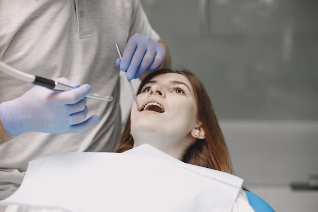 Paciente do sexo feminino com aparelho ortodôntico tem exame odontológico no consultório dentista. estomatologista usando luvas azuis