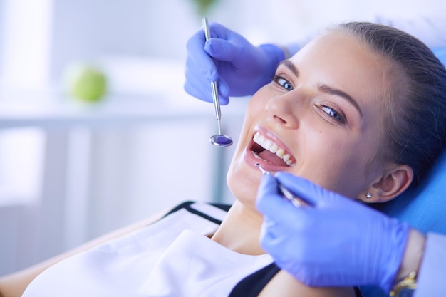 Paciente do sexo feminino jovem com boca aberta examinando a inspeção odontológica no consultório do dentista