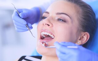 Foto paciente do sexo feminino jovem com boca aberta examinando a inspeção odontológica no consultório do dentista