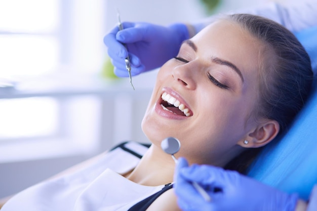Paciente do sexo feminino jovem com boca aberta examinando a inspeção odontológica no consultório do dentista