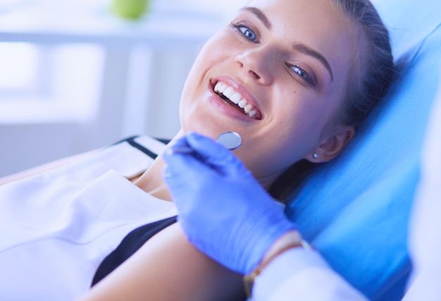 Paciente do sexo feminino jovem com sorriso bonito examinando a inspeção odontológica no consultório do dentista