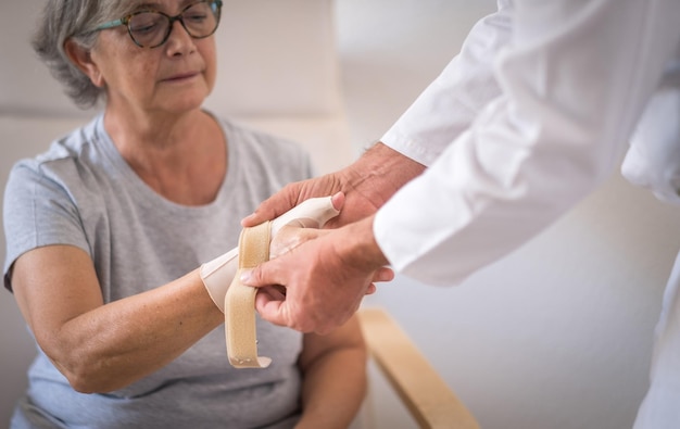 Paciente do sexo feminino sênior com rizoartrose do polegar direito enquanto usava uma cinta de polegar com seu fisioterapeuta dor de mulher idosa e reabilitação no centro médico