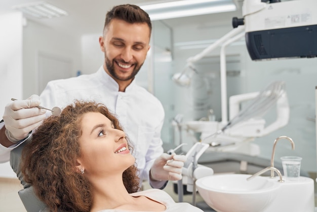 Paciente do sexo feminino sentado na cadeira enquanto médico examina os dentes