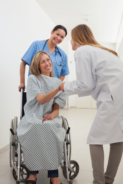 Paciente do sexo feminino sorridente, apertando a mão do médico