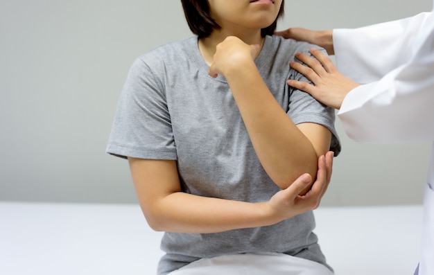 Foto paciente do sexo feminino vem ver um médico para verificar se há dor no cotovelo