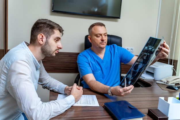 Paciente do sexo masculino no escritório após MRT Doctor explicando raio-x a um paciente