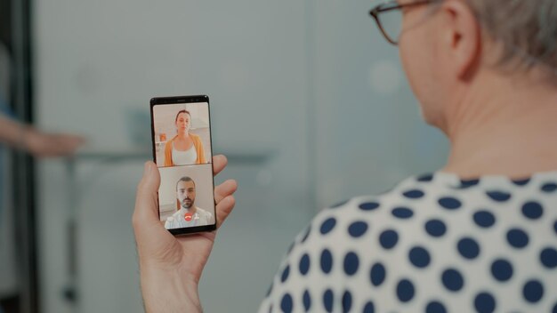 Paciente doente conversando em videochamada com parentes na enfermaria do hospital após cirurgia em unidade profissional. Velho usando smartphone para falar com a família sobre sistema de saúde e tratamento