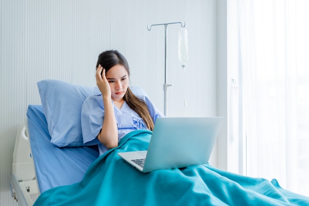 Paciente con dolor de cabeza en la cama con un portátil