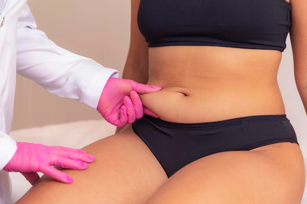 Paciente e esteticista realizando medições para procedimentos estéticos mulher em spa medindo sua barriga com fita métrica conceito de perda de peso