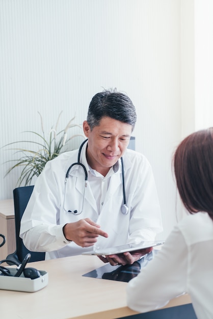 Paciente e médico asiático estão discutindo