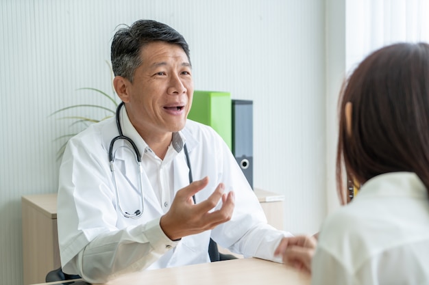 Paciente e médico sênior asiáticos estão discutindo