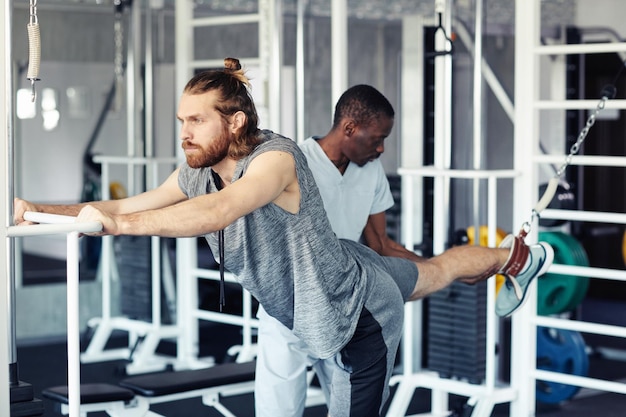 Paciente entrenando su pierna lesionada en el gimnasio