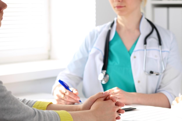 Paciente escuchando a su médico sentado en la mesa. Primer plano de las manos.