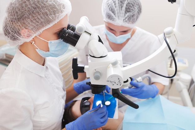 paciente de examen de dentista profesional con microscopio en la oficina