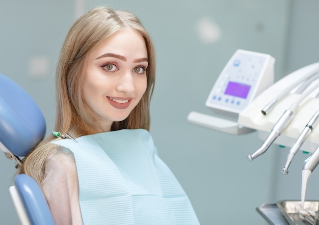 Un paciente feliz en una clínica dental se sienta en una silla.