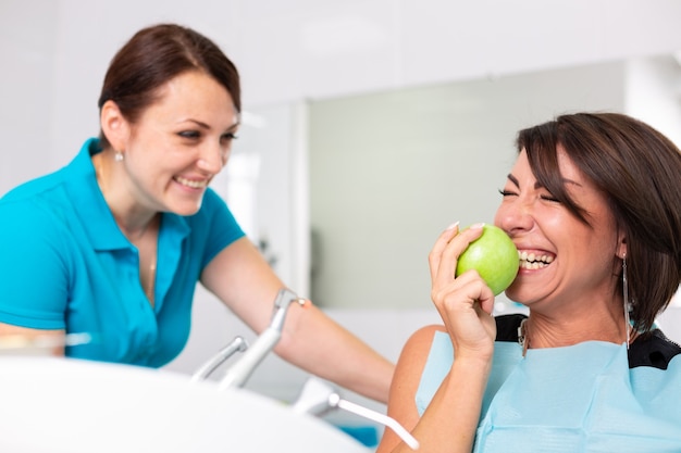 Un paciente feliz en la recepción del estamotólogo, comprueba la salud de los dientes, mordiendo el jaloc verde