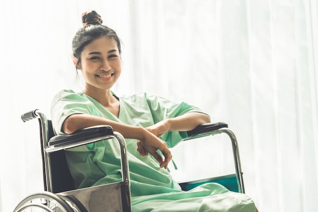 Paciente feliz sentado en silla de ruedas en el hospital. Fondo de salud médica.