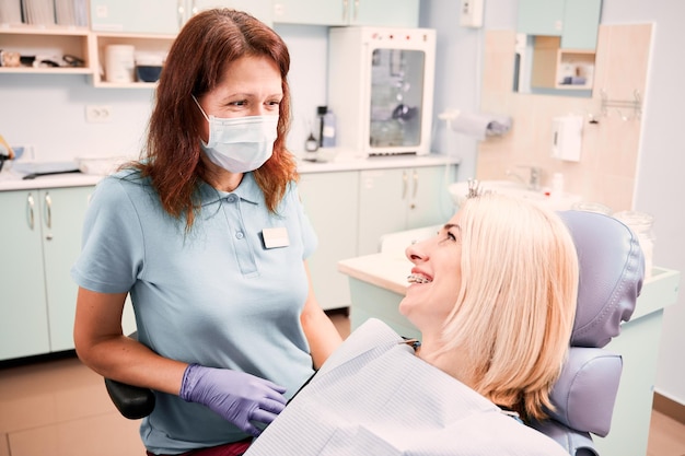 Paciente femenina alegre hablando con el médico en el consultorio dental