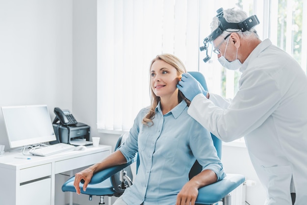 Foto paciente femenina de mediana edad que visita a un médico otorinolaringólogo