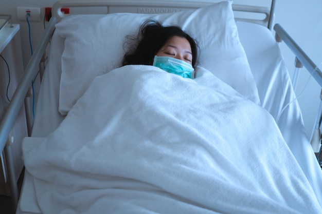 Foto paciente femenino asiático durmiendo en la cama del hospital para recuperar la enfermedad