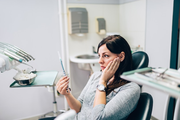 Paciente femenino asustado que mira la jeringuilla dental.