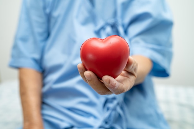 Paciente idosa asiática ou idosa segurando coração vermelho saudável conceito médico forte