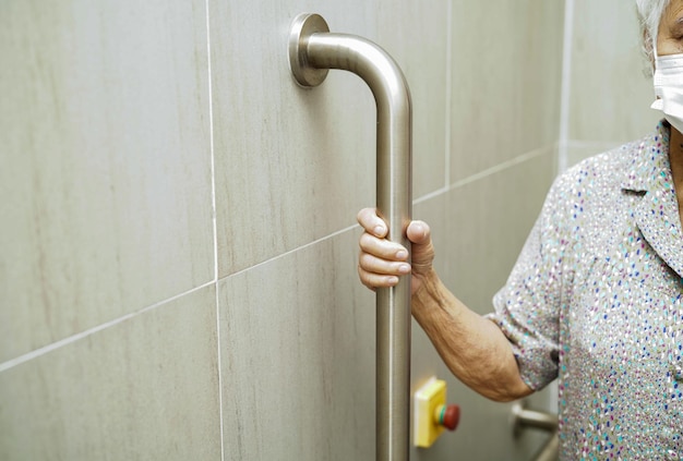 Paciente idosa asiática usa trilho de suporte do banheiro no corrimão do banheiro segurança da barra de segurança no hospital de enfermagem