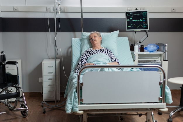 Paciente idosa deitada em uma cama de hospital