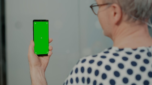 Paciente idoso segurando smartphone com tela verde na enfermaria do hospital para tratamento intensivo. Homem idoso isolado doente usando dispositivo e equipamento de tecnologia moderna para se recuperar de uma cirurgia