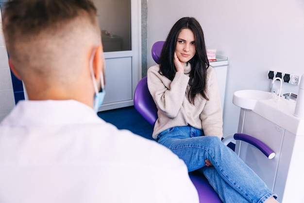 Paciente infeliz que tiene un dolor de muelas en una clínica dental en un sillón profesional. queja del paciente.